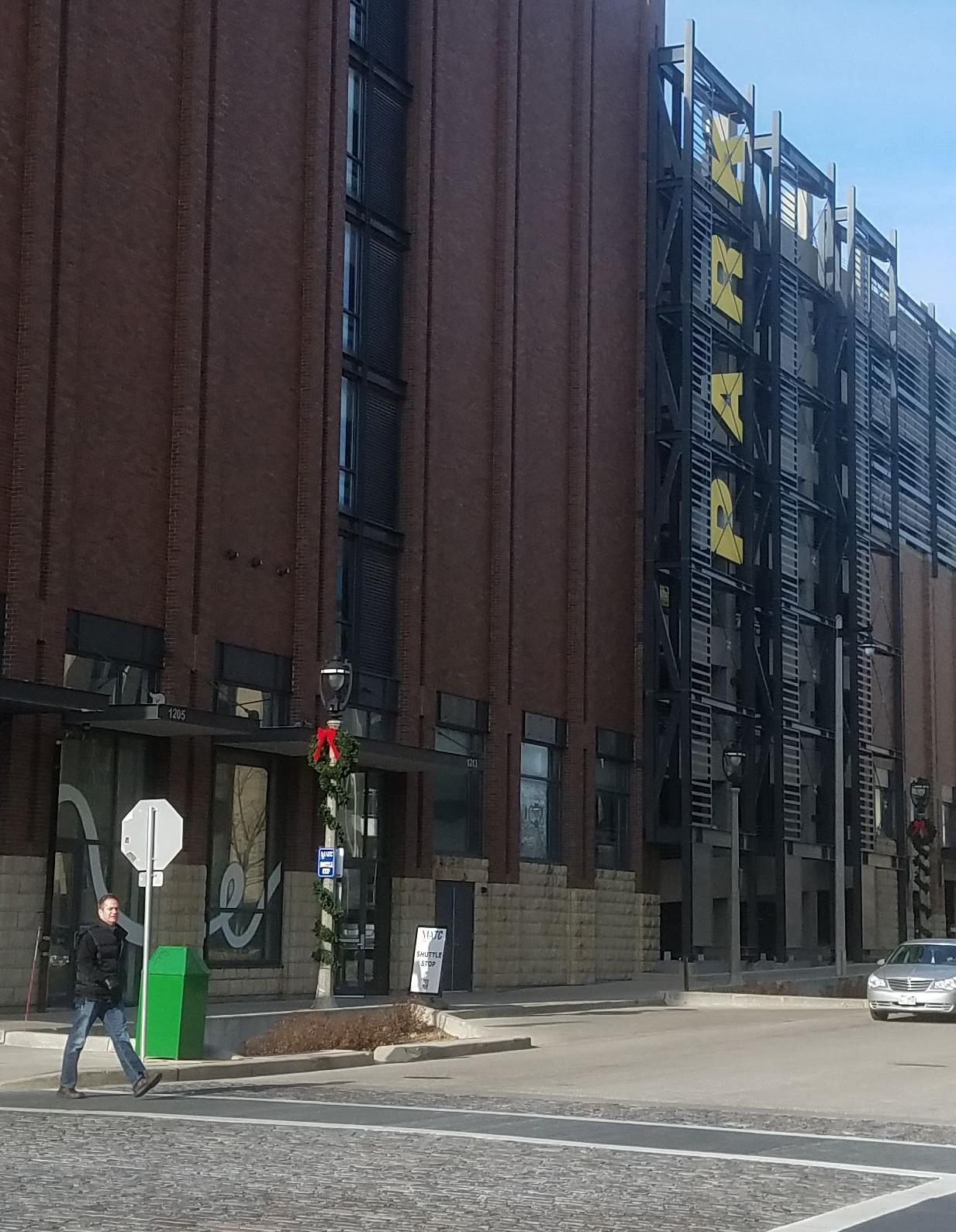 person crossing the crosswalk with parking ramp in the background