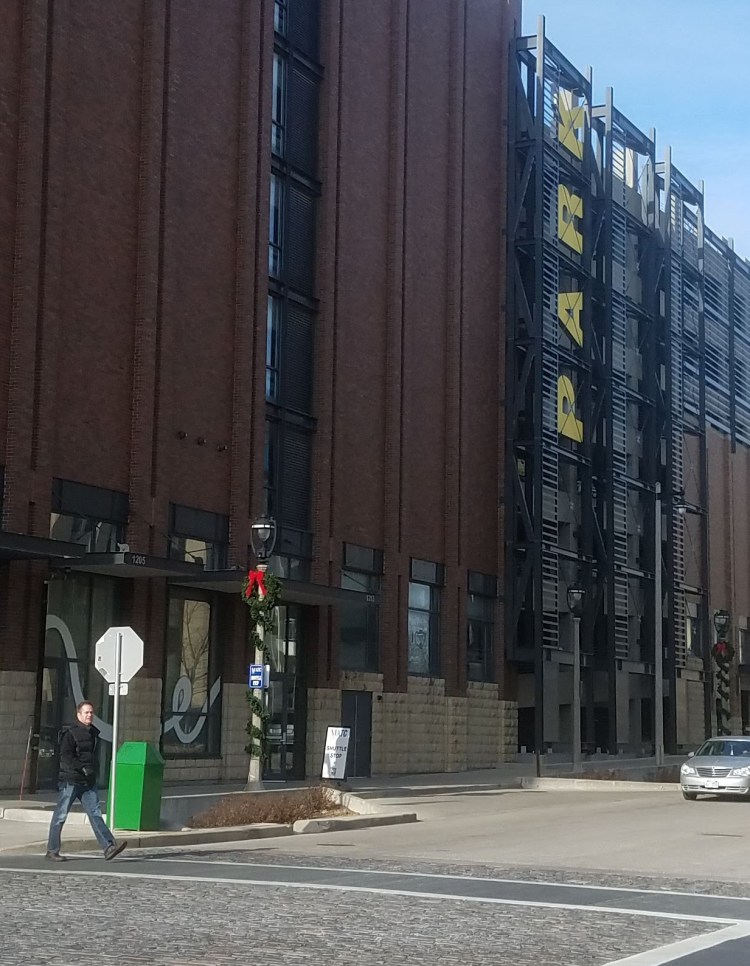 person crossing the crosswalk with parking ramp in the background