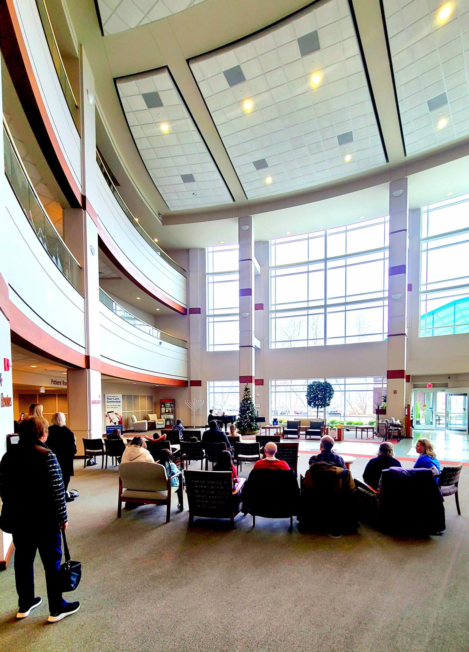 photo of student recital in a large room full of huge windows and a black mini grand piano